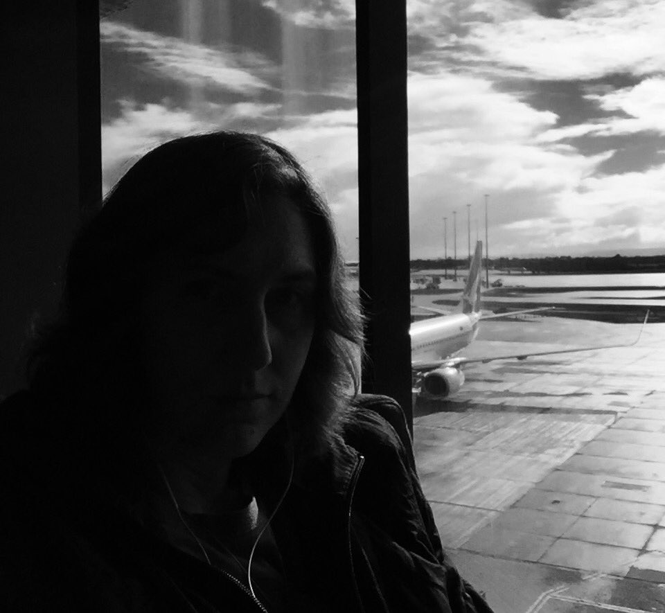 Very dark half-shadowed black & white selfie with an airplane in the background (out the window)