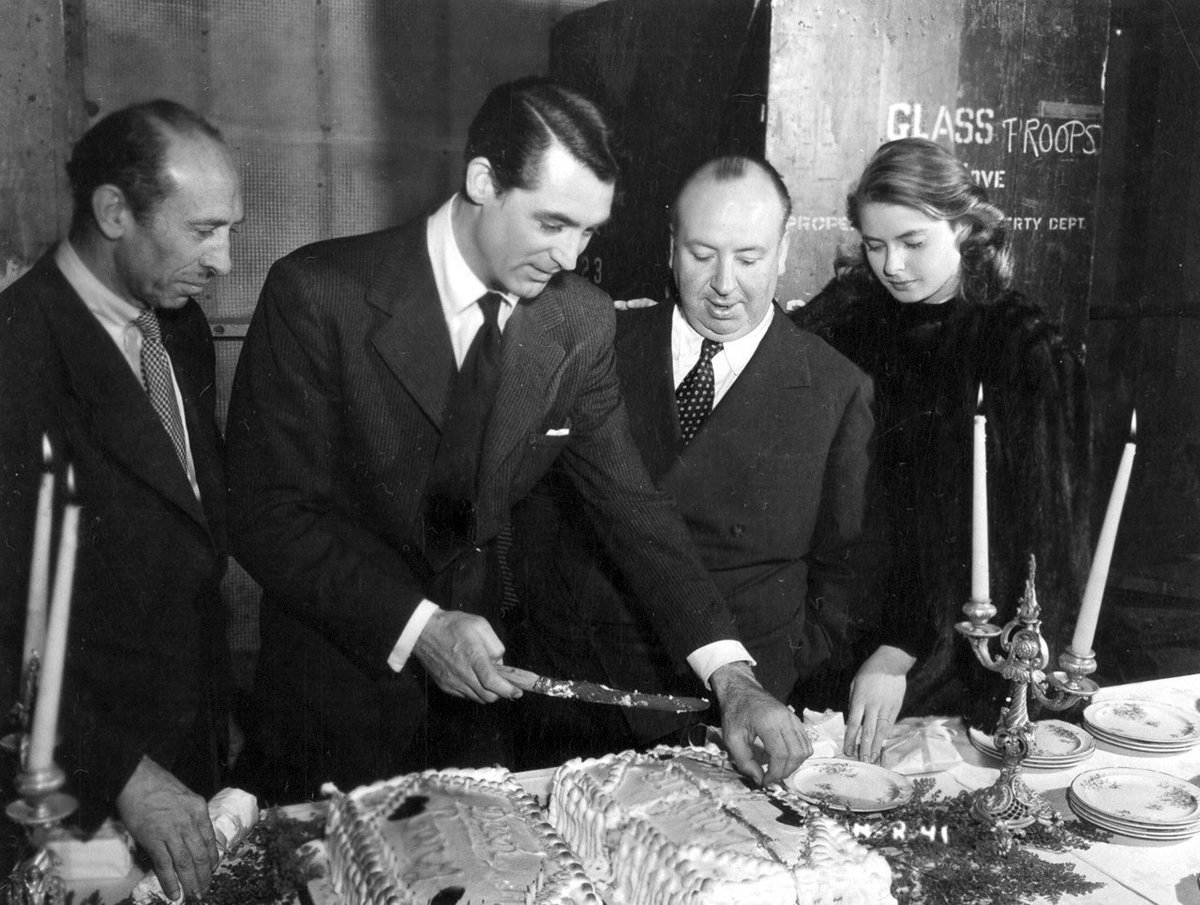 distractedfilm's tweet photo. NOTORIOUS:

Cary Grant cuts his Birthday cake on the set of “Nororious"” as Alfred Hitchcock and Ingrid Bergman look on, 1946 . https://t.co/JSQZnMamPK