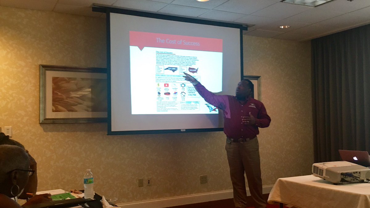 Photo: picture of Jamaal Mayo pointing at a PowerPoint slide on cost-of-attendance