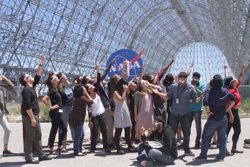 NASAInterns's tweet photo. Interns at @NASAAmes βhangingβ out by historical Hanger One preparing for #eclipse2017 with their new shades! Vote by liking & sharing! https://t.co/JySjO2df2j