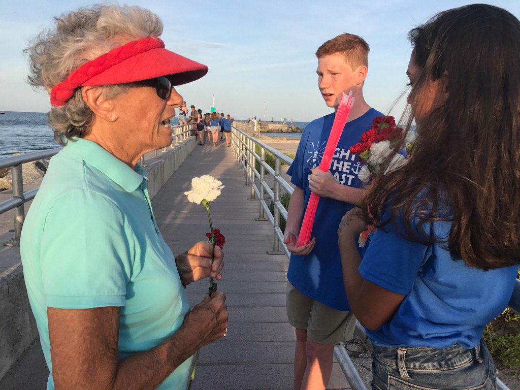 M_Quesada's tweet photo. Family, friends of #AustinAndPerry hand out glow sticks and flowers for tonight's anniversary vigil. @WPTV https://t.co/3tbZ20zQw1
