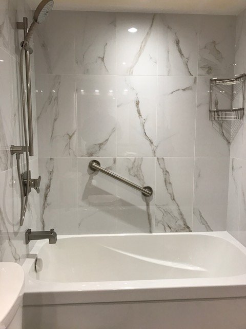 Clean and streamlined tub update with grab bar and slide shower rail for easy accessibility