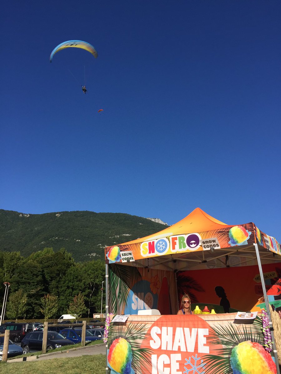 TeamSnoFro's tweet photo. Lake annecy paragliding parapente landing site serving Hawaiian Shave Ice to this crazy lot! #snowcones #teamsnofro #snofro #shaveice https://t.co/UmcFB9WCQf