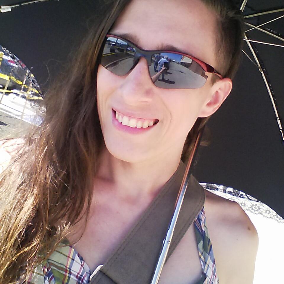 Sabriel in sunglasses under a parasol.