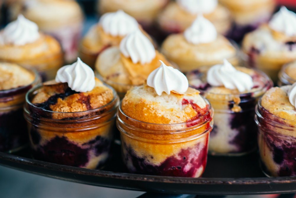 The groom's mother made these summer berry cobblers in mini mason jars for bride Olivia's shower. See more here: ultimatebridesmaid.com/2017/08/28/sum…