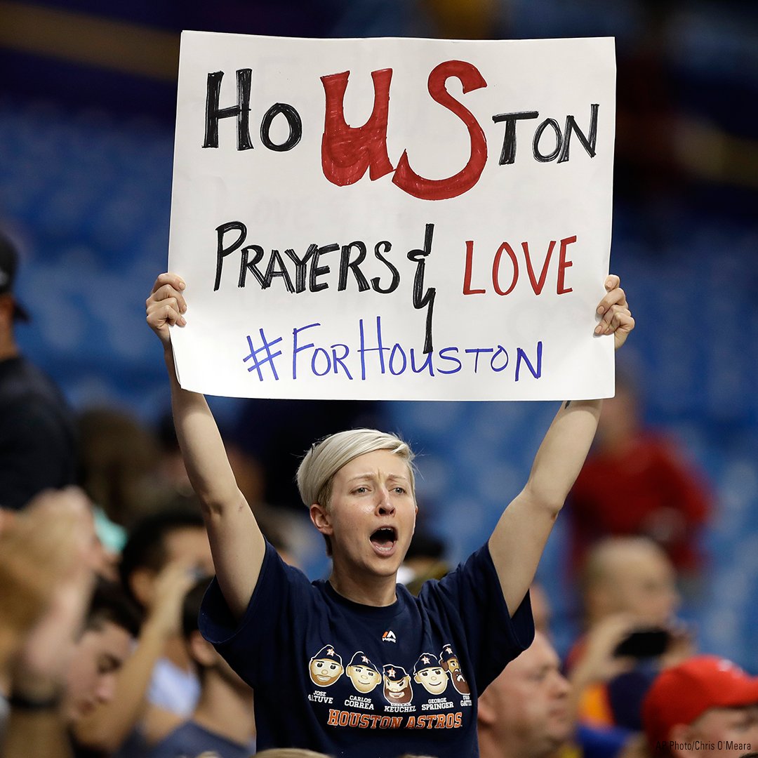 A woman holds up a sign during the first inning of an <a href="/astros/">Houston Astros</a> baseball game that was moved due to unsafe conditions from Hurricane Harvey.