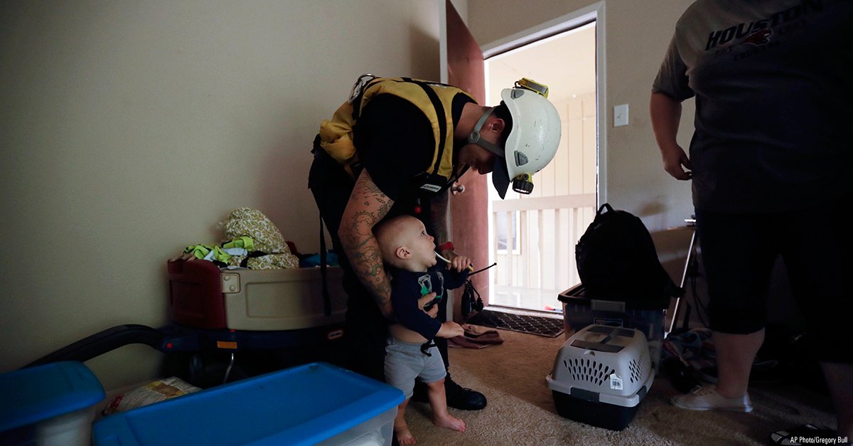 A firefighter greets a six-month-old boy as he helps rescue the family from their apartment due to floodwaters from Tropical Storm Harvey.