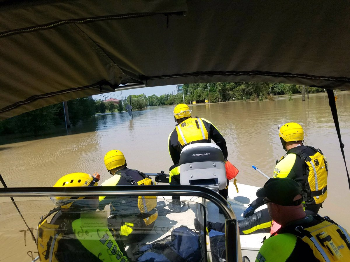 Five search and rescue personnel in a boat on the floodwater.