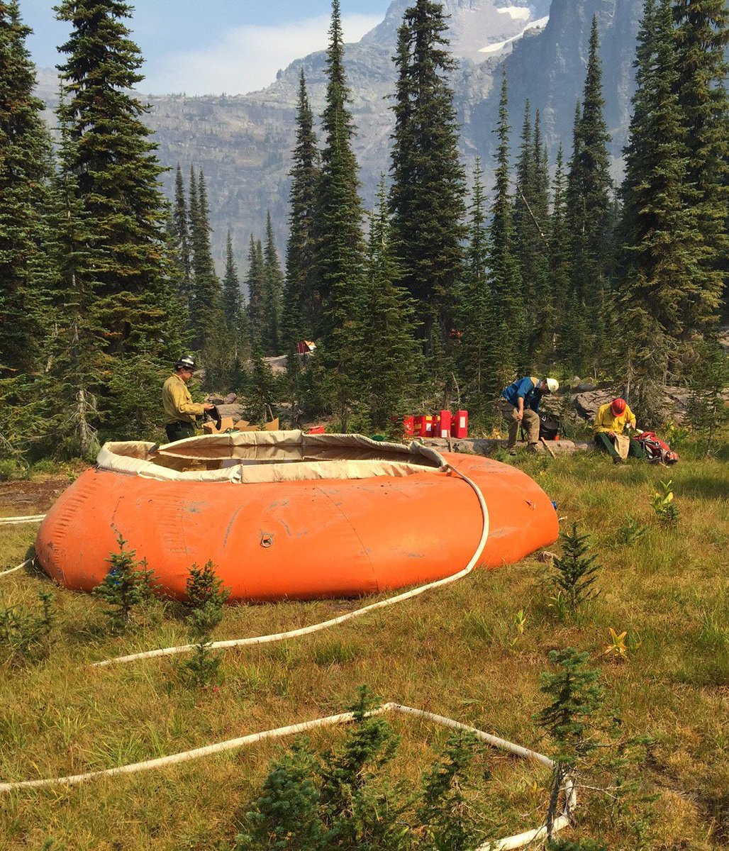 GlacierNPS's tweet photo. Firefighters near Sperry Chalet break for lunch at a portable water tank called a pumpkin #SpragueFire #glacierNPS #WildlandFire https://t.co/63oI7matIp