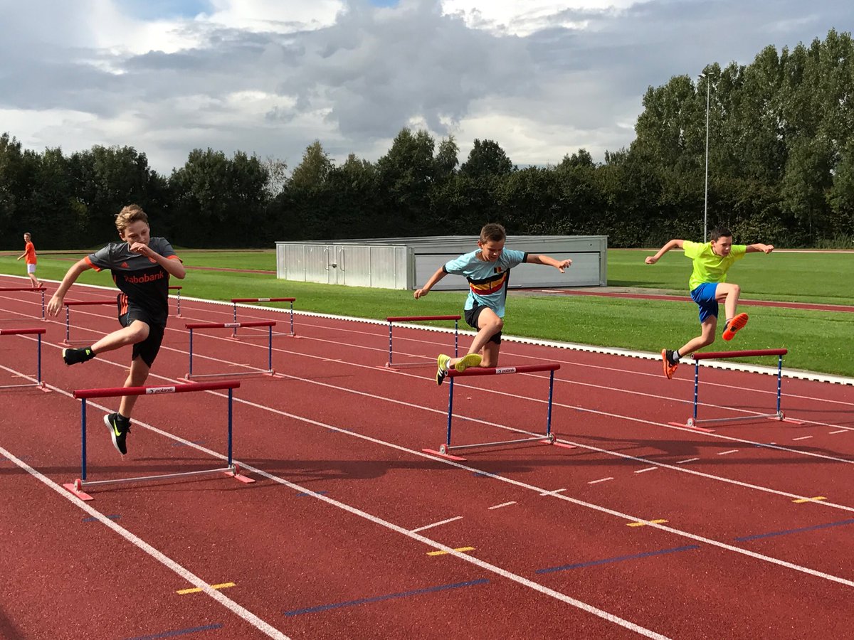Sportklassers krijgen les hordeloop en polsstokhoogspringen op een echte atletiekbaan.