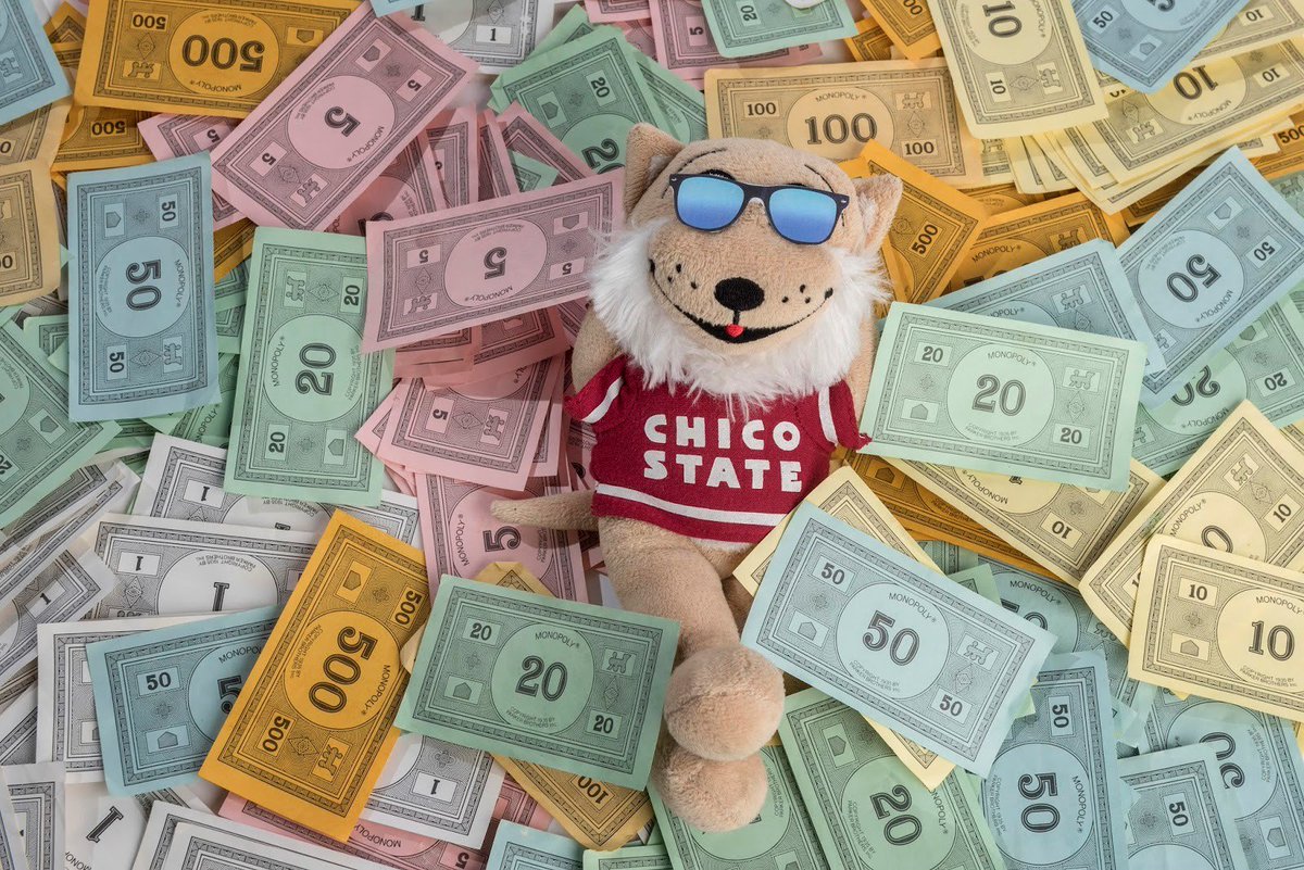 A doll of Willie the Wildcat, Chico State's mascot, relaxes in a pile of Monopoly money.