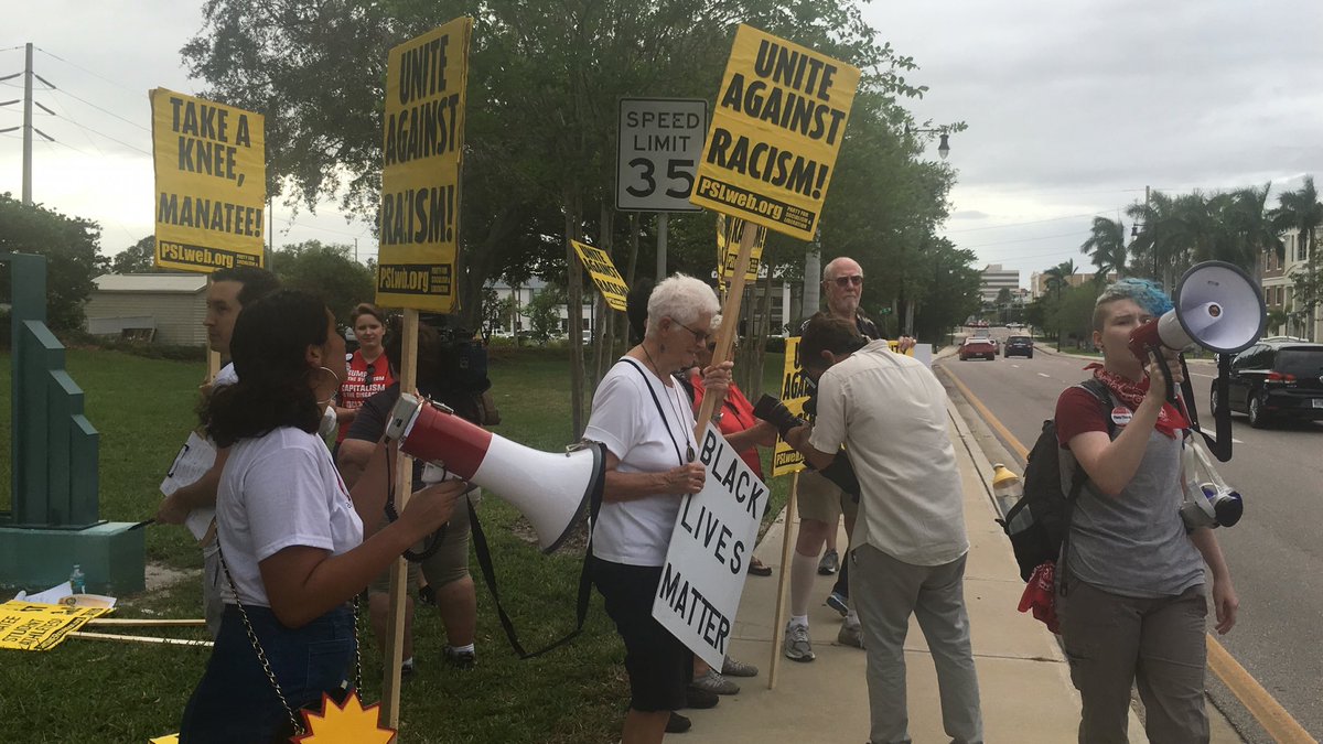 Protesters lift signs in front of the Manatee school district Tuesday calling citizens to unite against racism.