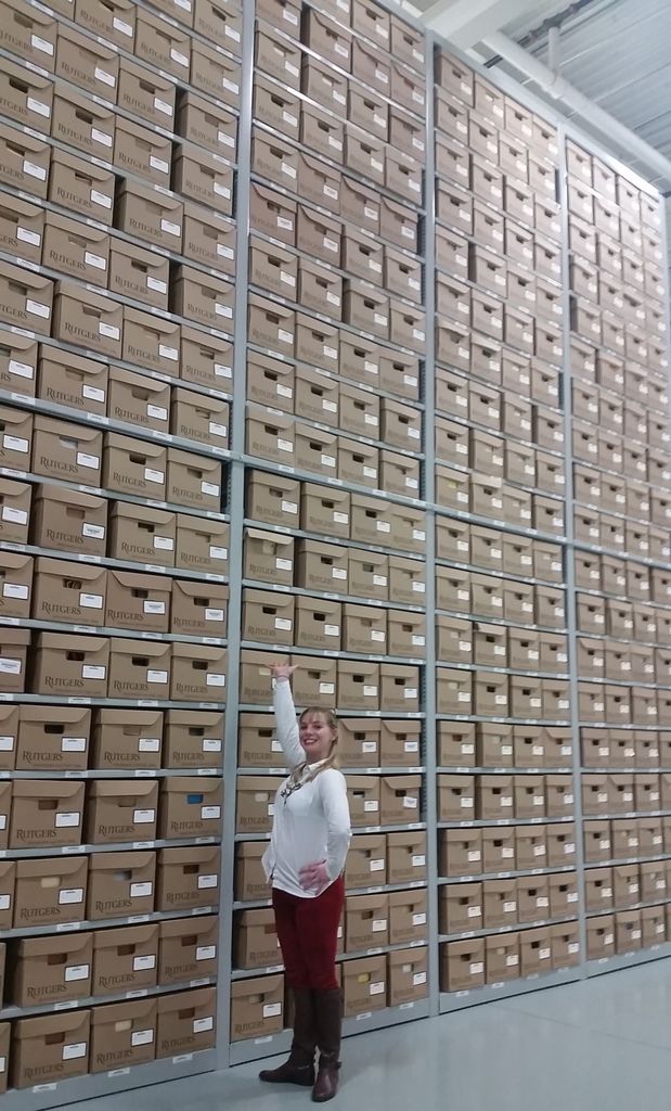 Archivist standing in front of a wall of boxes that is floor to ceiling.