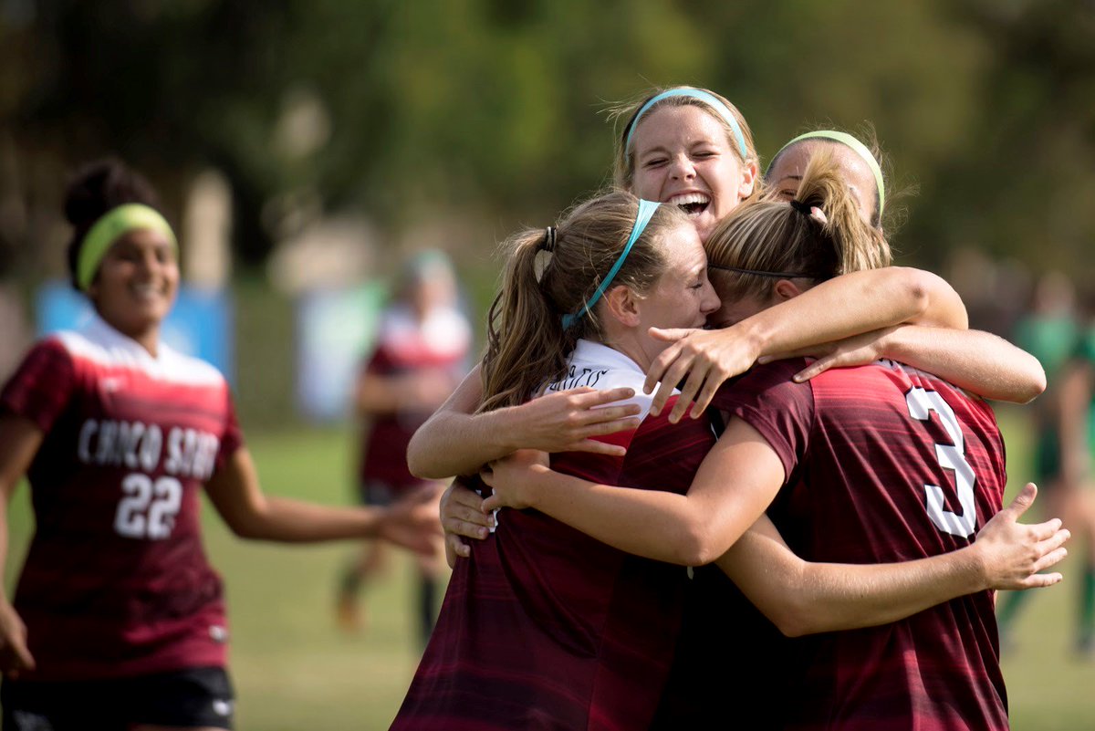 Chico State women's soccer players celebrate with a group hug.