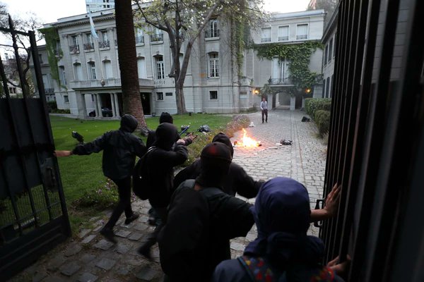 infobae's tweet photo. Encapuchados provocaron destrozos en el consulado argentino en Chile tras una protesta por Santiago Maldonado https://t.co/UnGmfLuiTh https://t.co/MVLfFy6HpO