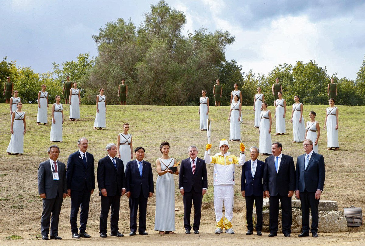 iocmedia's tweet photo. The Olympic Flame and first torch bearer surrounded by President Bach and the NOC Presidents of future Games from Pyeongchang to Los Angeles https://t.co/sY1KuBMcju