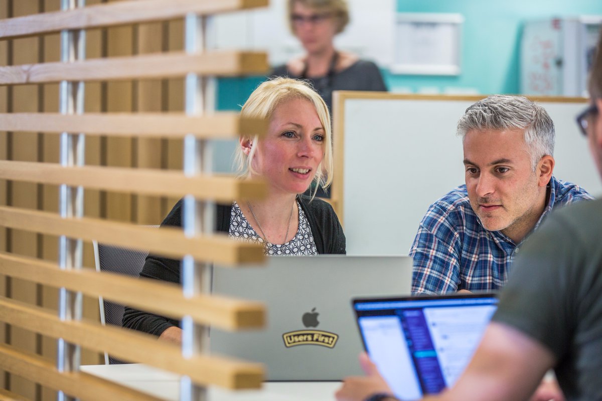 Photo of young woman and young man looking into laptop screens in office