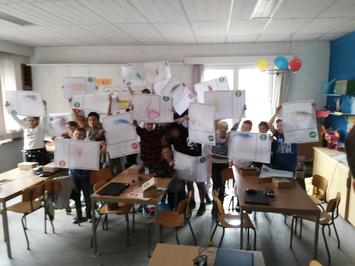 A class proudly showing their drawings.