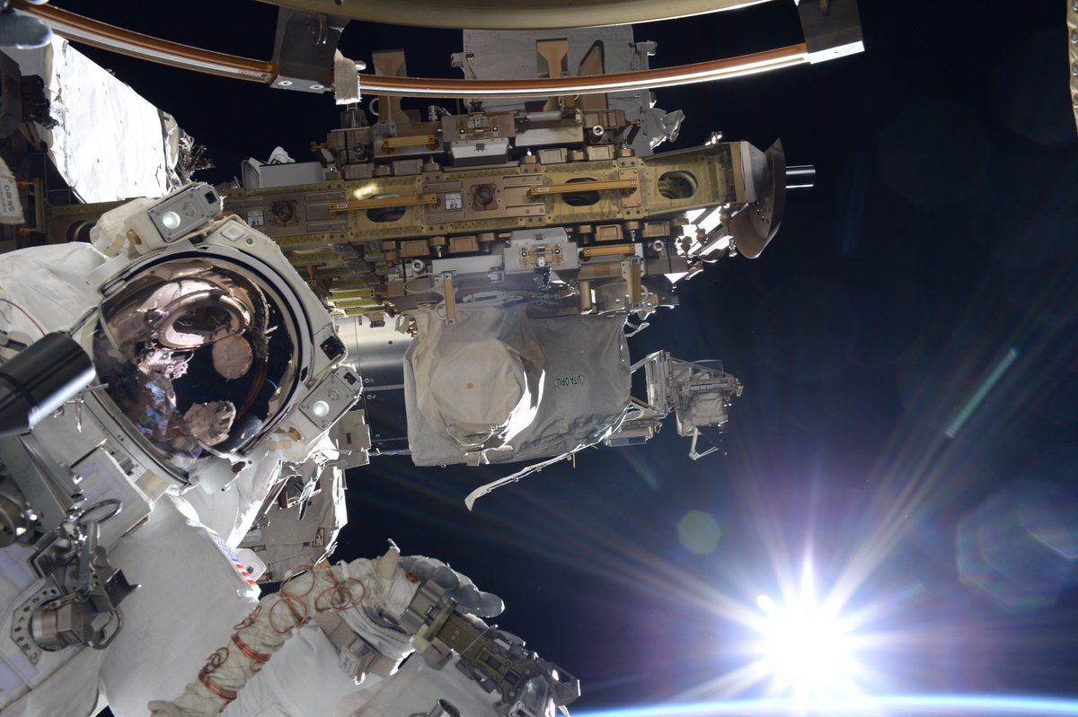 AstroKomrade's tweet photo. A glorious sunrise greeted @Astro_Sabot and I at the start of our 2nd #spacewalk. His visor reflection shows the airlock hatch we came out. https://t.co/yMwFCSmE5c