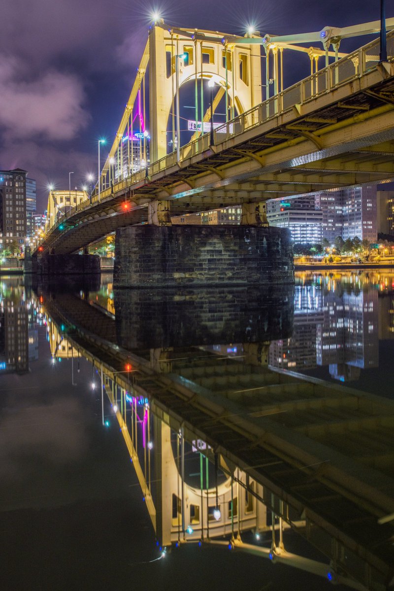 DaveDiCello's tweet photo. The Clemente Bridge in #Pittsburgh frames the spire of the Highmark Building as it reflects in the still waters of the Allegheny River https://t.co/QfyzGERk7n