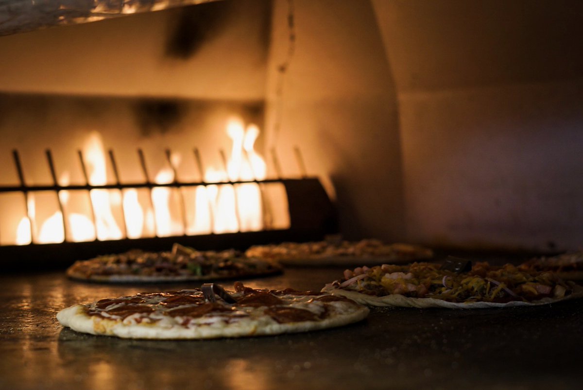Custom pizzas cooking in our custom gas fired open hearth oven in about 5 minutes.