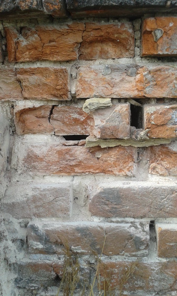 Crumbling brick and gaping hole on a chimney. This will be repaired properly before being thatched over,thus avoiding a possible fire.