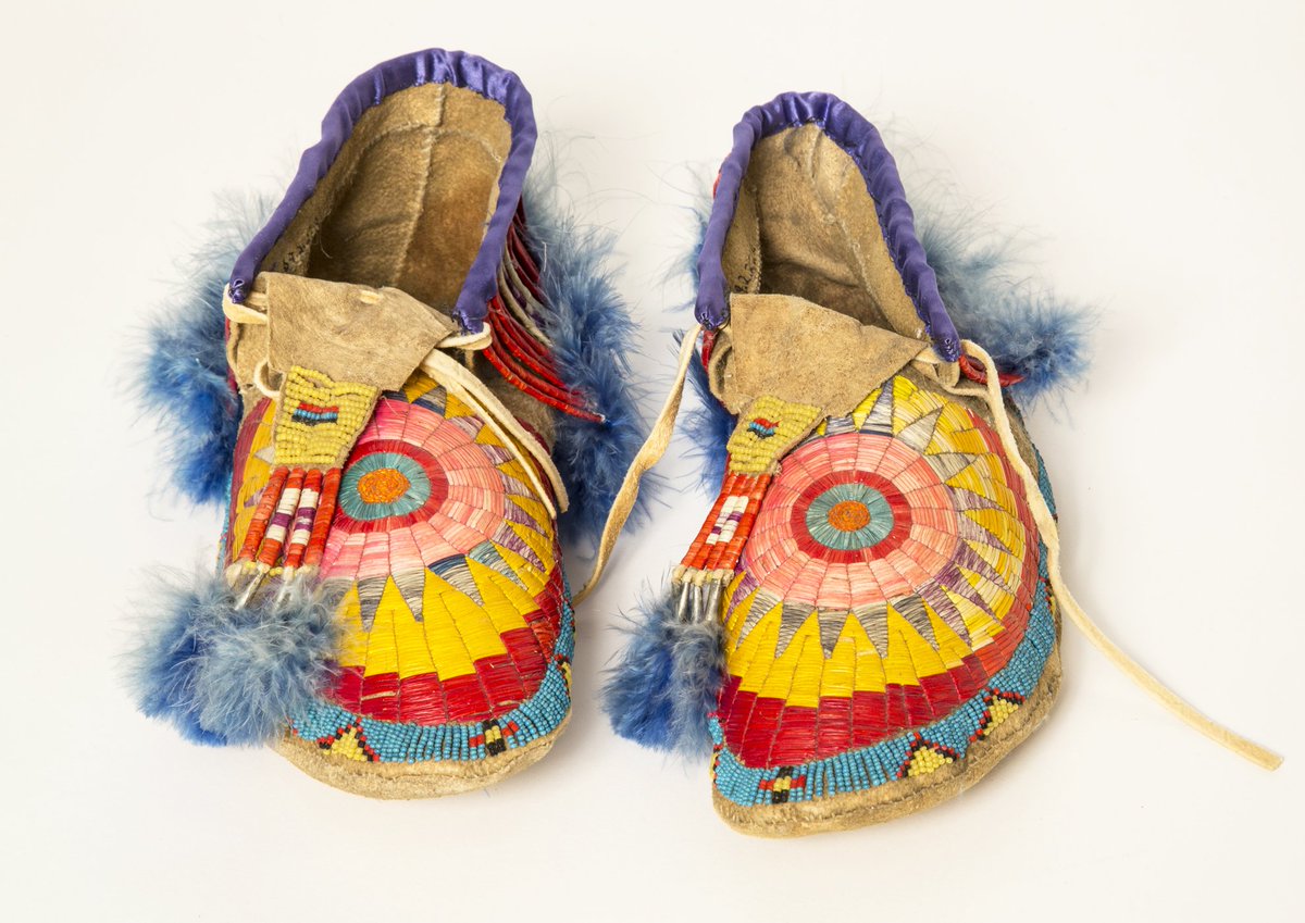 An pair of leather moccasins is decorated with beads and feathers.