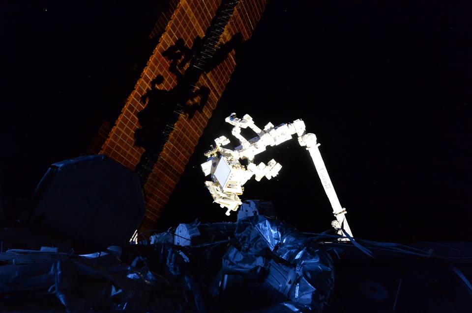 csa_asc's tweet photo. Canadarm2 is casting a shadow on a solar array while the rest of the ISS is shrouded in darkness. Credit: ESA/NASA https://t.co/4Vj2RU2V08