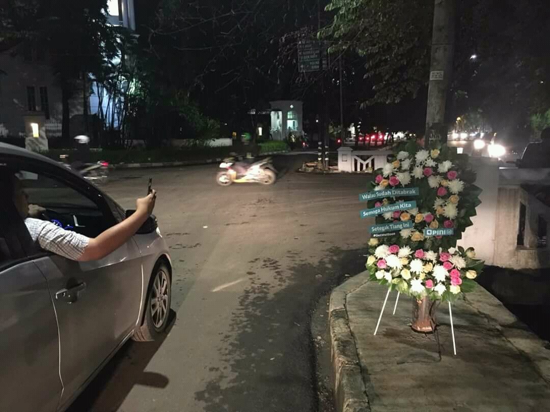 Publik mengabadikan karangan bunga untuk tiang listrik