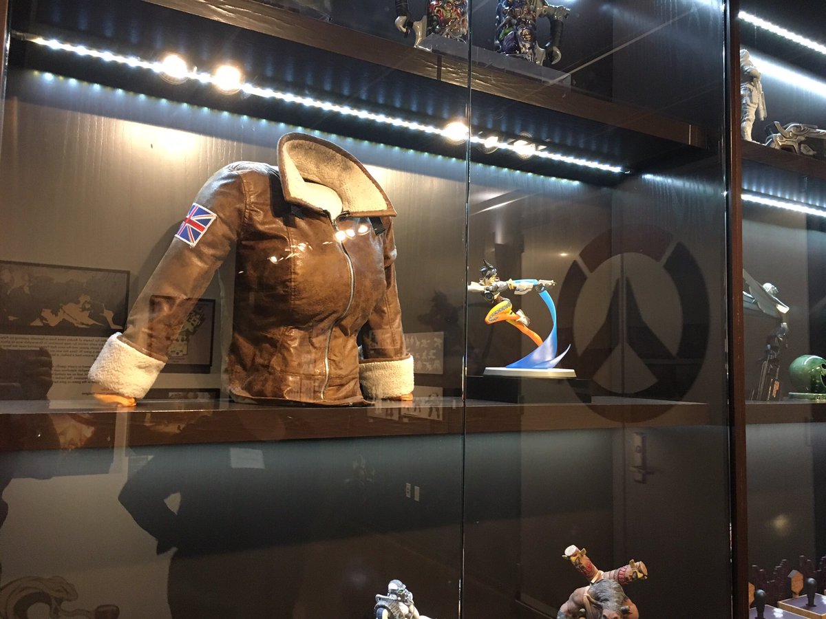 A display case with Tracer’s bomber jacket and a statue of Tracer next to it
