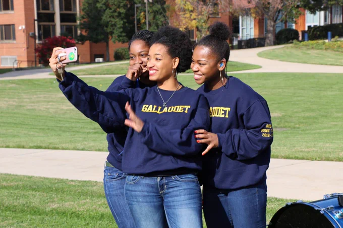 [Image description: Three Bison Song members stand together to take a photo from an iPhone. They all are looking towards the camera.]