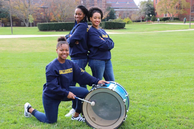 [Image description: Three Bison Song members pose in their Bison Song positions for the photo. They all are wearing the Bison Song sweater.]