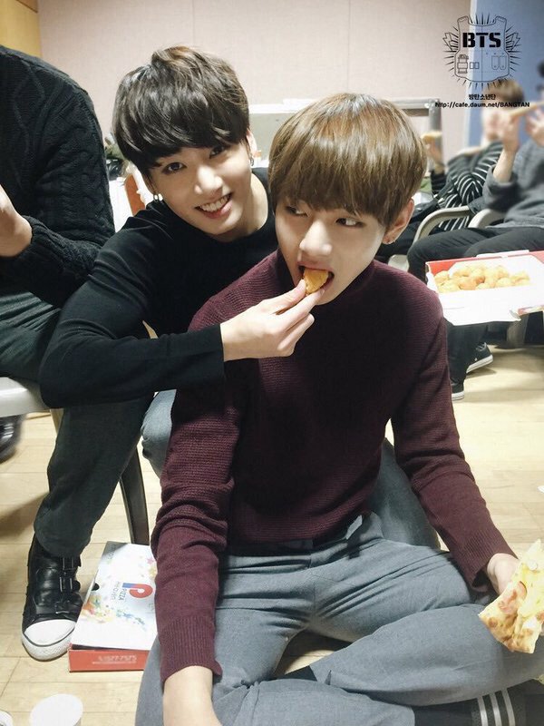 —; Jungkook feeding Taehyung a snack  [2016] (see how diff they look even tho it's taken on the same year hsndh)