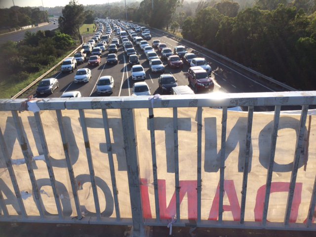 Alan_Cuthbert's tweet photo. It's day 4 of our 5 day campaign. The #StopAdani banner on 5 freeways in 5 days. We are on the footbridge in Clifton Hill over the Eastern Freeway. Cars all stopped to read it! Let's stop ADANI! #5Days5Fwys #QuitCoal https://t.co/yQGY5c26Rm
