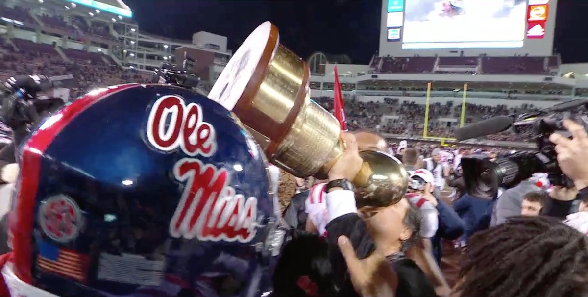 SpiritBen's tweet photo. Matt Luke, his players surrounding him hollering, 'We love you, coach!,' kisses the Egg Bowl trophy. https://t.co/1vpjTavumW
