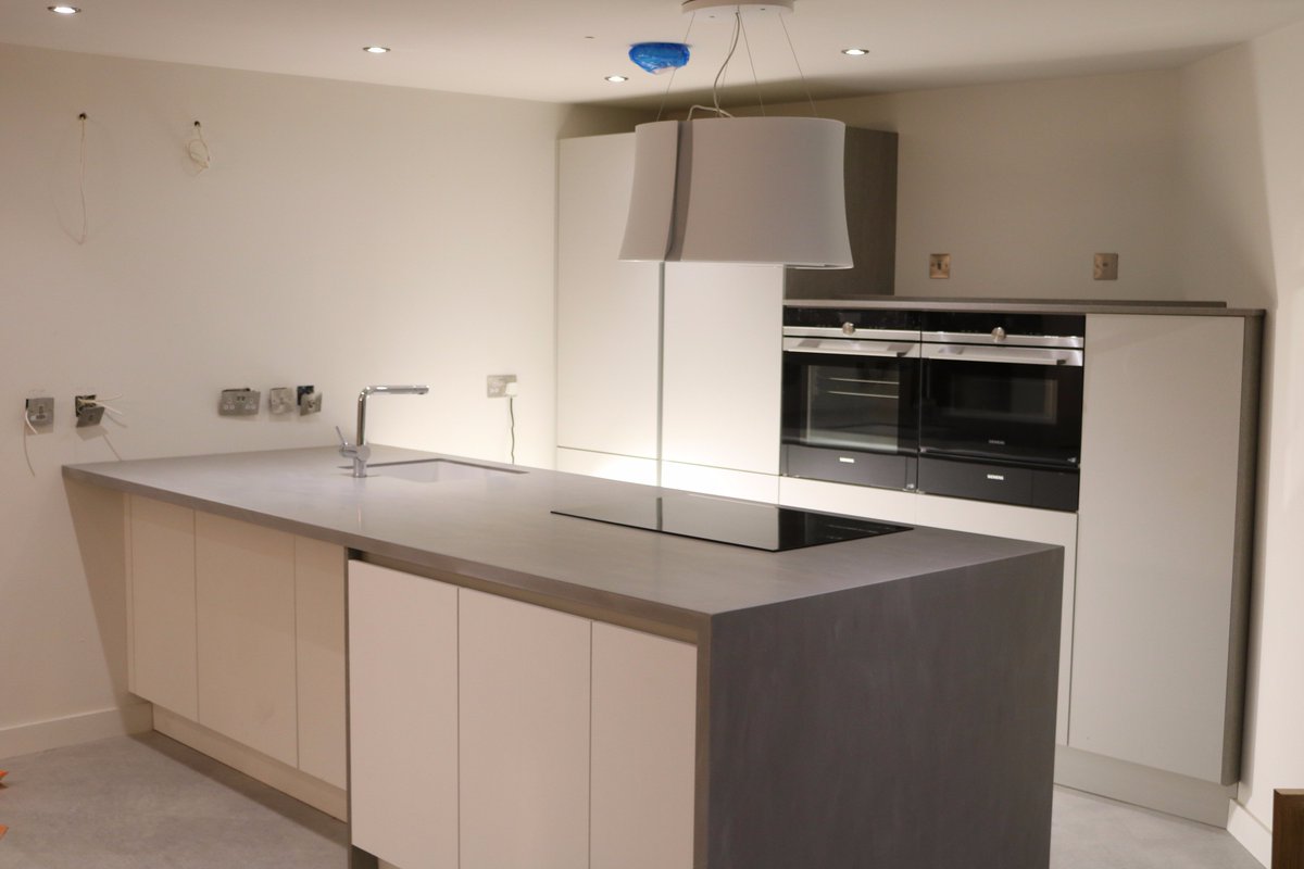 White and grey laminate furniture with Neutral concrete corian tops and corian avante sink complimented by Siemens appliances.