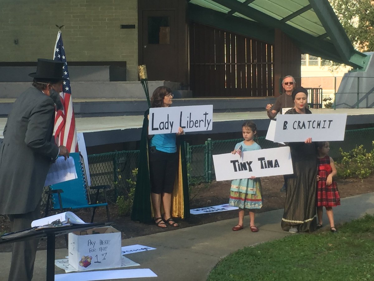 ForOurFutureFL's tweet photo. Today in St Pete: Residents protest with tax-themed Christmas Carols and sketches
(To the tune of: “Winter Wonderland”) 
🎼Gone away, the estate tax
Corporate rates, get a sharp axe
They’re singing a song,
while loopholes stay strong,
Fight to end the GOP tax scam!🎼 https://t.co/EQKpUK0aBJ