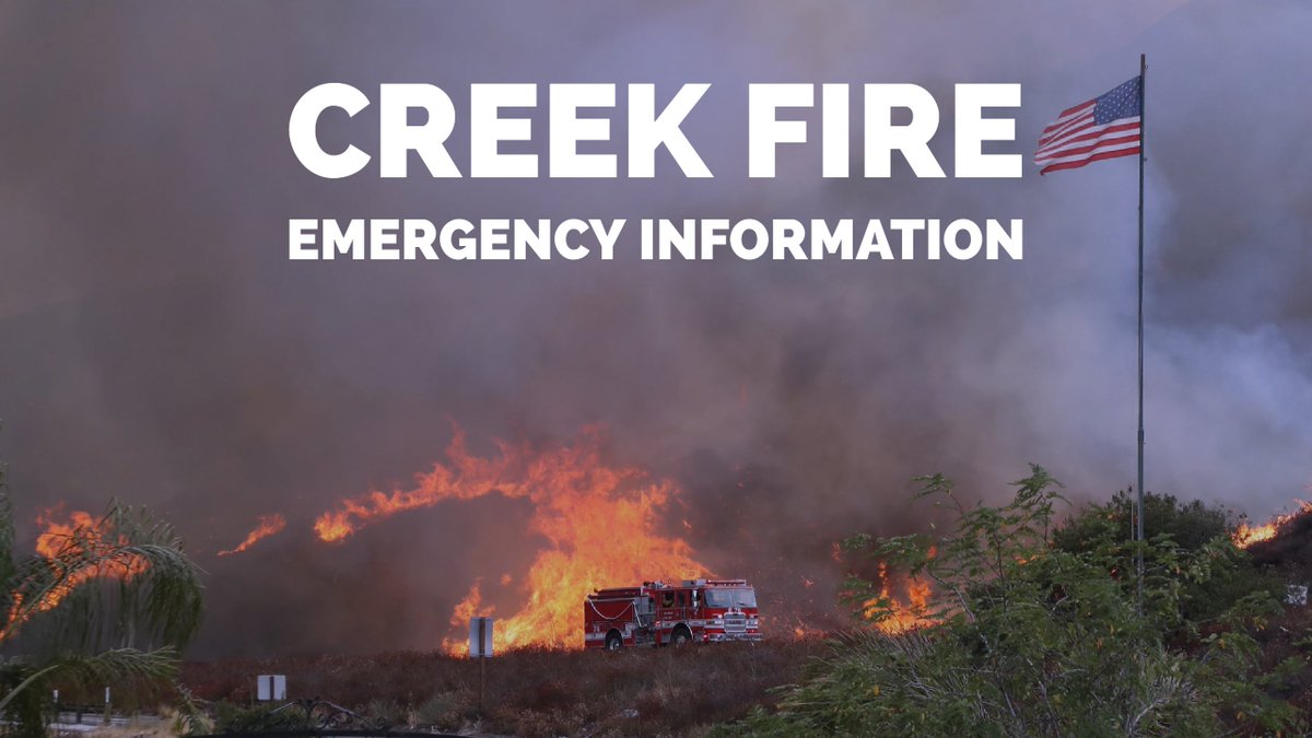 Image of a fire truck racing ahead of a burning hillside. An American flag waves on the right side of the photo. Text: CREEK FIRE EMERGENCY INFORMATION