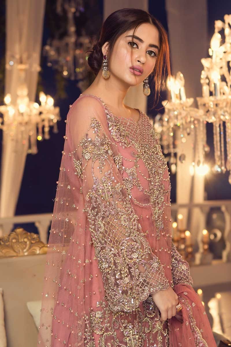 sajal aly pink dress The iconic Sajal Ali in our Rosen Bridal A blush-toned masterpiece adorned with Austrian Swarovski crystals and intricate hand-embellishments. A poetic expression of grace, luminosity, and timeless couture elegance. #trousseaubyst #