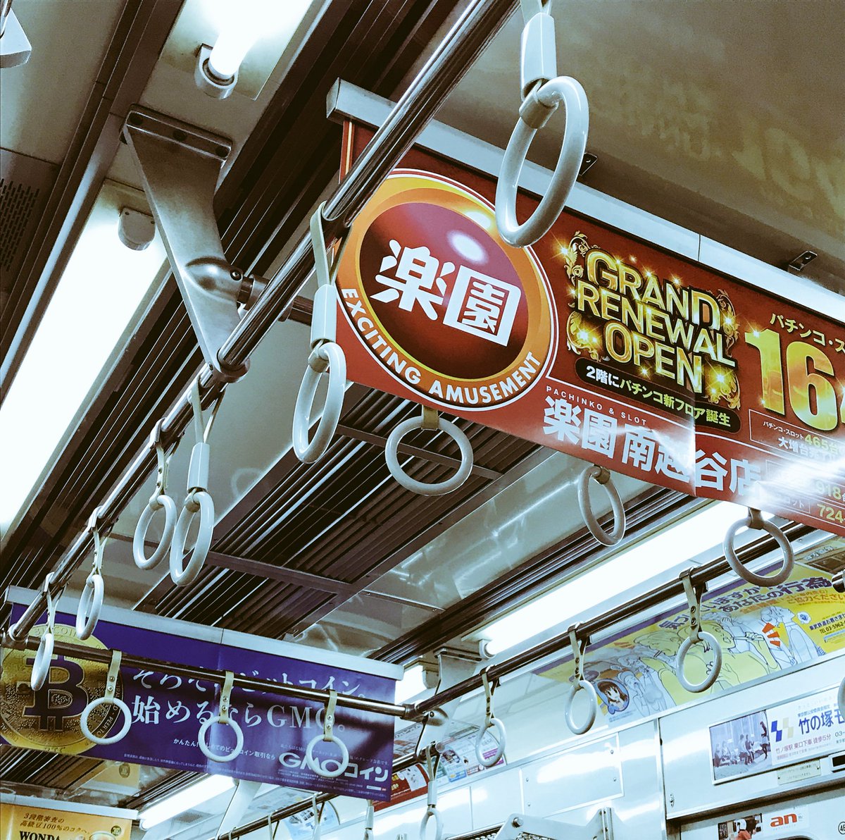 パチンコ広告とビットコイン広告の並ぶ電車内。