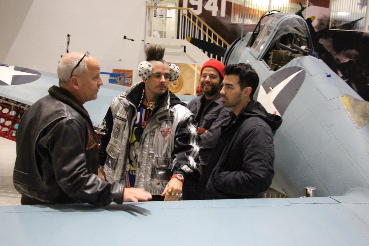 USAA's tweet photo. The group @DNCE tours the @NavalMuseum w/museum director USN Capt. (Ret) Sterling Gilliam, before going onstage at #USAABaseFest. https://t.co/oJquZ8n5XL