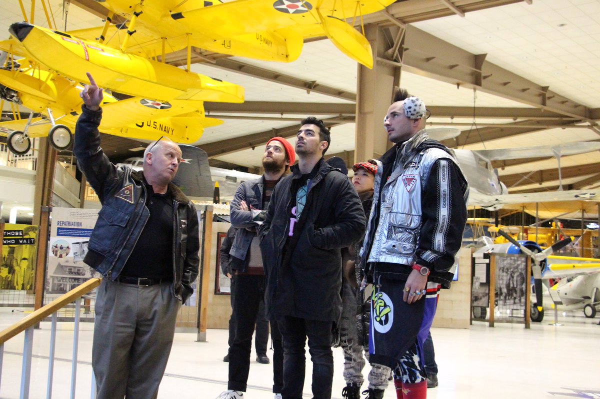 USAA's tweet photo. The group @DNCE tours the @NavalMuseum w/museum director USN Capt. (Ret) Sterling Gilliam, before going onstage at #USAABaseFest. https://t.co/oJquZ8n5XL