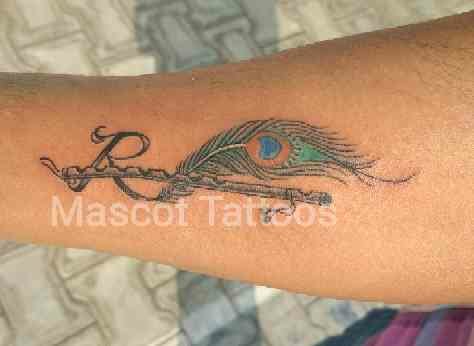 Peacock Feather With Flute Tattoo On Forearm