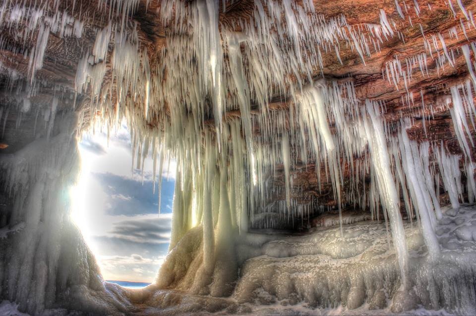 Large spiky icicles hang from the ceiling of a cave.