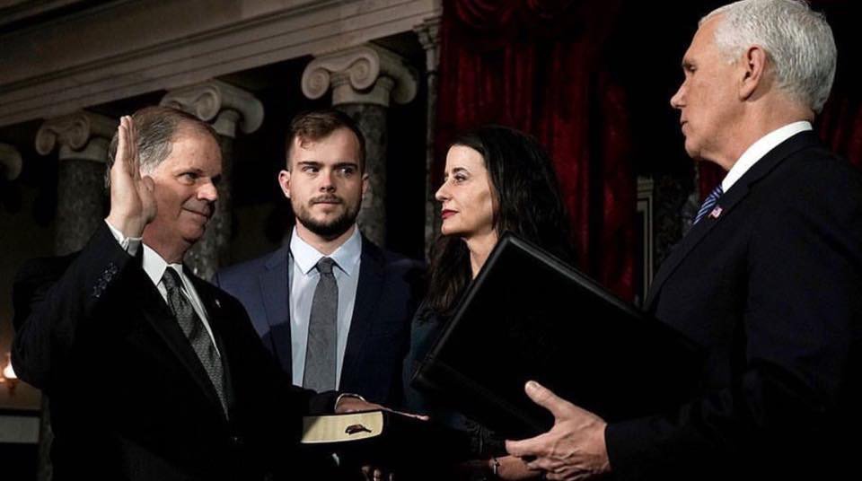 Photo of the decade: Doug Jones being sworn in, while his openly gay son QUIETLY DISINTEGRATES THE SOUL OF MIKE PENCE.
