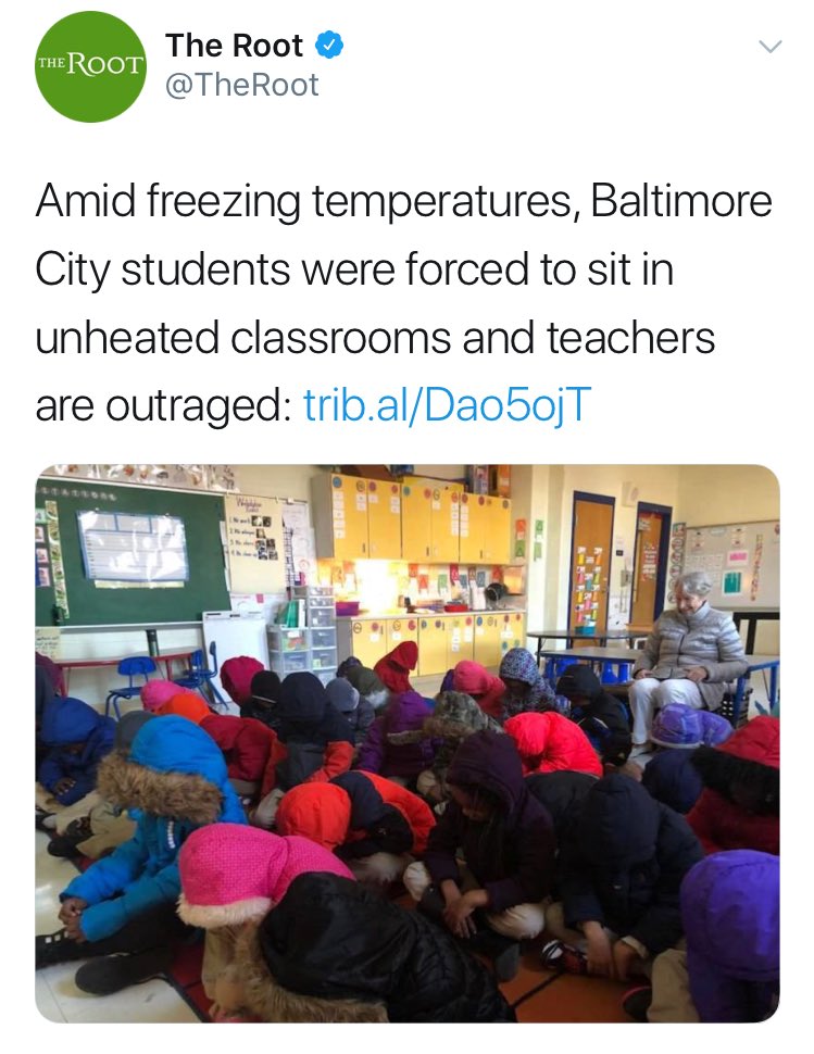 picture of small children huddled together wearing jackets inside a classroom in Baltimore