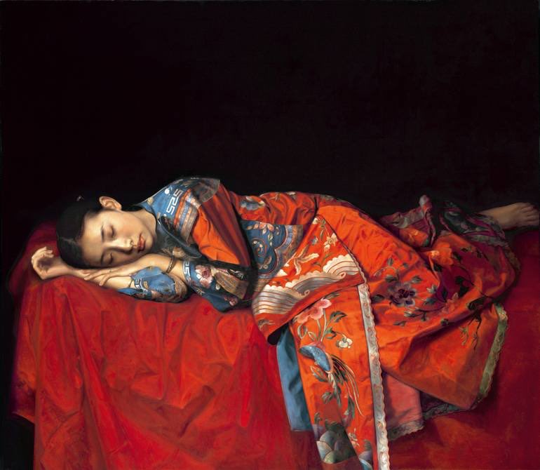 Beautiful traditional pose of Chinese girl in a red traditional Chinese printed robe laying on a red sheet