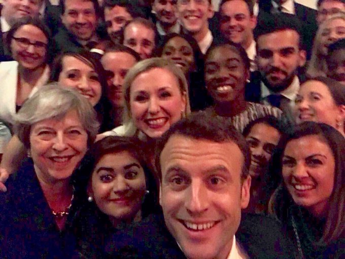 The picture is a selfie of Prime Minister Theresa May, French President Macron and a large group of people - taken at the V&A museum in London.