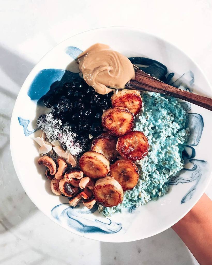 Mermaid Latte Oats 🧜‍♀️🌊🐳 with caramelized bananas, maple syrup glazed blueberries, coconut toasted cashews and a spoon of creamy ol' nut butter. 🤤 This is my go to breakfast treat, on a super busy day - keeps me energized and so satisfied for 3-5 hours to get loads of w…