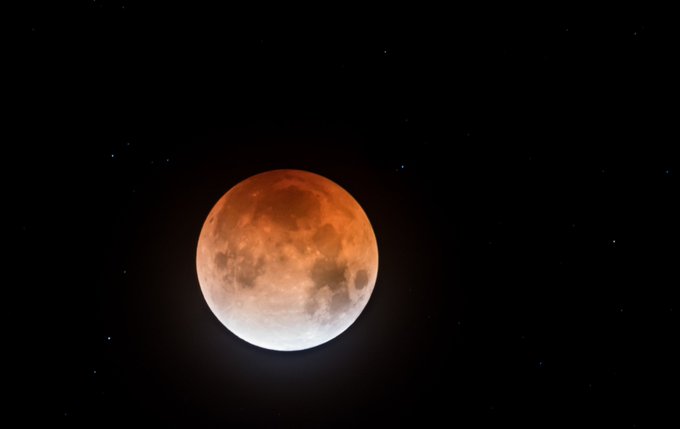 A photo of the night sky shows a large full moon tinted red.